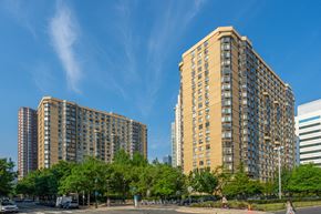 Jersey City apartment for rent - Two large buildings are surrounded by trees and a blue sky.
