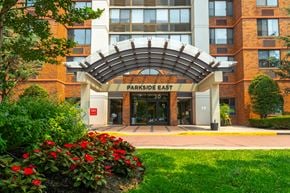 Jersey City apartment for rent - The front of a building called Parkside East with a red flower bed in front.