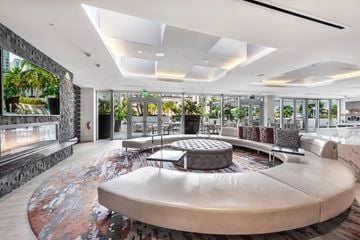 Miami apartment for rent - A modern living room with a large circular sofa and a fireplace.