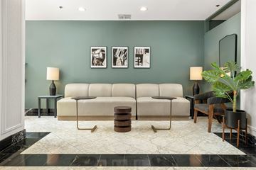 Jersey City apartment for rent - A living room with a beige sofa, two lamps, a table, and a potted plant.
