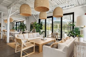 North Miami apartment for rent - A living room with a white couch, wooden chairs, and a large window.
