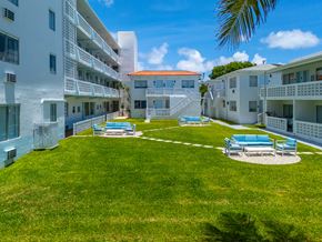 Miami apartment for rent - A sunny day at the courtyard of a white apartment building.