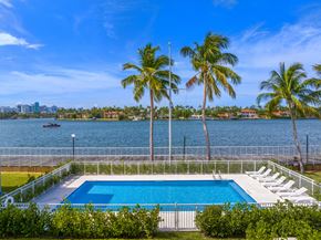 Miami apartment for rent - A pool surrounded by palm trees and a city skyline in the distance.