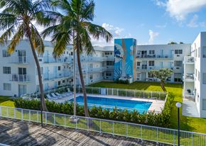 Miami apartment for rent - A pool surrounded by a fence and palm trees.
