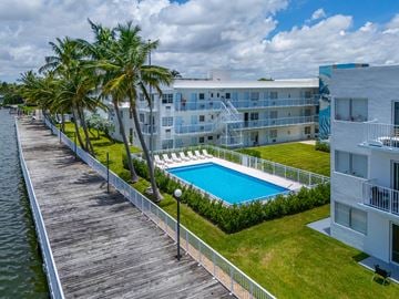 Miami apartment for rent - A pool is surrounded by a fence and a building is in the background.