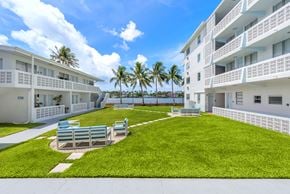Miami apartment for rent - A white building with balconies and a green lawn in front.