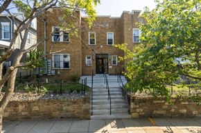 Washington apartment for rent - A brick building with a black iron fence and a stone wall in front.