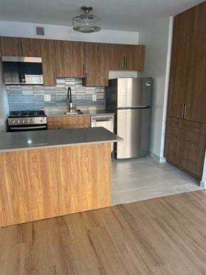 Washington apartment for rent - A kitchen with wooden cabinets and a stainless steel refrigerator. at 2400 Pennsylvania Avenue Apartments, Washington, DC,20037