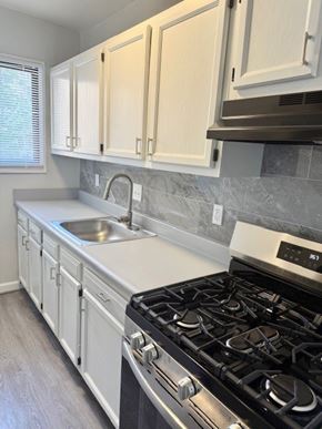 Washington apartment for rent - A kitchen with a black stove top oven and white cabinets.