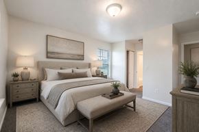 Canal Winchester apartment for rent - A bedroom with a large bed and a bench in front of it.