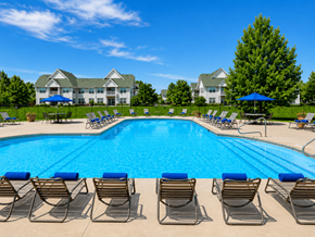 Canal Winchester apartment for rent - A swimming pool surrounded by lounge chairs and umbrellas with a building in the background.