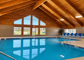 West Chanhassen apartment for rent - A large indoor swimming pool with a wooden ceiling and a view of the outdoors through the windows.