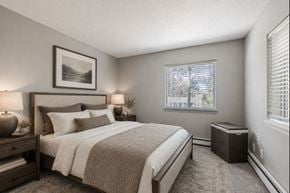 Eagan apartment for rent - A bedroom with a large bed and a window with blinds.