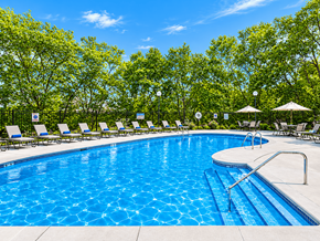Eagan apartment for rent - A swimming pool surrounded by trees and lounge chairs.