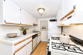 East Point townhouse for rent - Galley kitchen with white cabinets and gas stove at Stonetree Apartments, East Point, GA