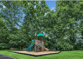 Charlottesville apartment for rent - A playground with a green slide and a brown structure surrounded by trees.