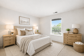 Charlottesville apartment for rent - A well-lit bedroom with a large bed, two nightstands, and a window showing an outdoor view.