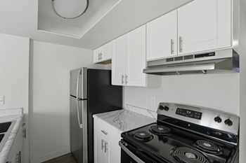 A kitchen with a black stove top oven and white cabinets.