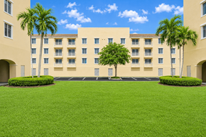 Lauderdale Lakes apartment for rent - A large building with a green lawn in front and palm trees on the side.