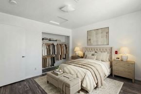 Henderson apartment for rent - A bedroom with a large bed, a clothing rack, and a nightstand with lamps.