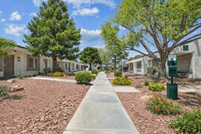 Henderson apartment for rent - A concrete pathway leads through a row of houses with trees on either side.