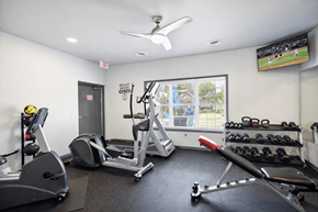 Cudahy apartment for rent - A gym with a row of treadmills, a stationary bike, a rowing machine, and a television showing a baseball game.