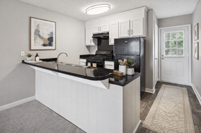 Concord apartment for rent - A kitchen with a black fridge and stove top oven.