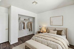 Henderson apartment for rent - A bedroom with a bed, a bench, and a closet with clothes.