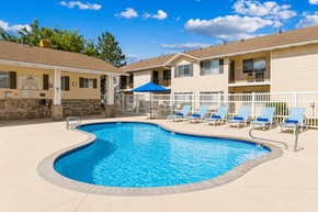 Cedar City apartment for rent - A swimming pool in a residential area with a blue umbrella.