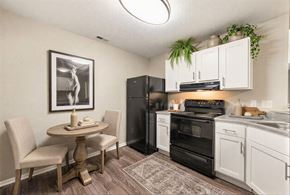 Charlotte apartment for rent - A kitchen with a black refrigerator, white cabinets, and a table with chairs.