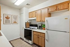 Henderson apartment for rent - A kitchen with a white refrigerator, wooden cabinets, and a stove top oven.