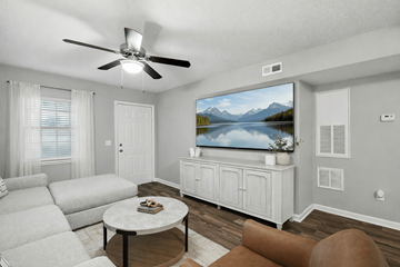 Mooresville apartment for rent - A living room with a white couch, a coffee table, and a television displaying a mountain landscape.
