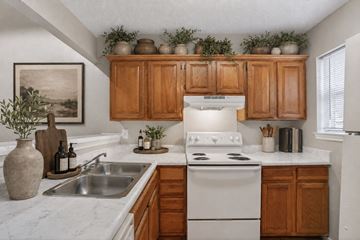 Dallas townhouse for rent - A kitchen with wooden cabinets and a white stove top oven.