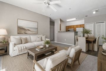 Fort Myers apartment for rent - A living room with a white couch, a wooden coffee table, and a painting of a beach scene on the wall.