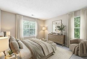 Charlotte apartment for rent - A well-lit bedroom with a large bed, a chair, and a nightstand with a plant on it.