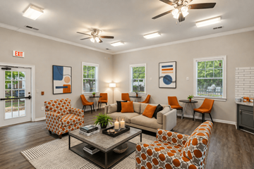 Newnan apartment for rent - A living room with orange and white furniture and a ceiling fan.