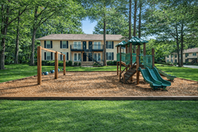 Jonesboro apartment for rent - A playground with a green slide and a wooden swing set in front of a two-story house.