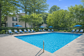 Jonesboro apartment for rent - A large swimming pool surrounded by trees and lounge chairs.