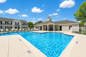 Saginaw apartment for rent - A large swimming pool in front of a building with a white fence around it.