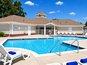 Southfield apartment for rent - A pool area with a building and lounge chairs.