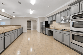 Katy apartment for rent - A spacious kitchen with grey cabinets and black appliances.