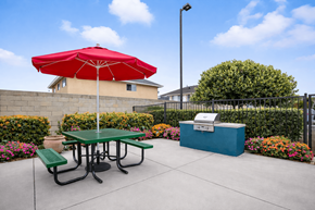 Huntington Beach apartment for rent - A red umbrella is on a green picnic table.