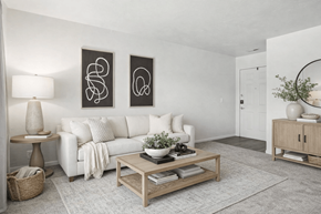 West Valley City apartment for rent - A living room with a white couch, a coffee table, and two abstract art pieces on the wall.
