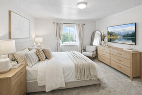 West Valley City apartment for rent - A bedroom with a large bed, a dresser, and a painting on the wall.
