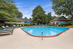Roswell apartment for rent - A swimming pool surrounded by lounge chairs and trees.