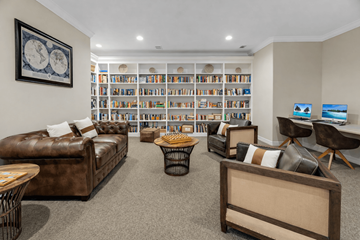 Katy apartment for rent - A living room with a brown leather couch, a coffee table, and a bookshelf filled with books.