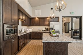 Meridian apartment for rent - Clubhouse kitchen with dark wood cabinetry and granite island at Harper Ridge Apartments, Idaho, 83642