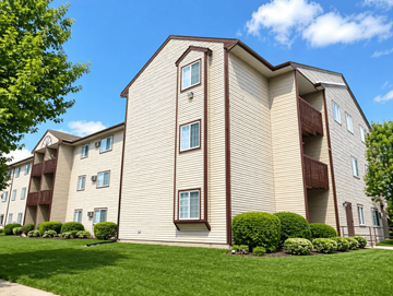 Lansing apartment for rent - A large apartment building with a green lawn in front.