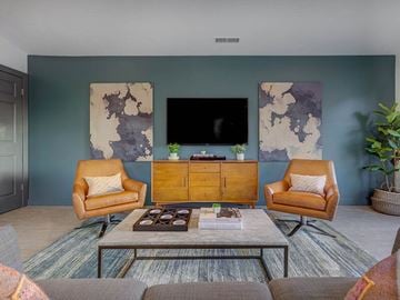 Midvale apartment for rent - A living room with a brown chair, a brown armchair, a brown coffee table, a flat screen TV, and two paintings on the wall.