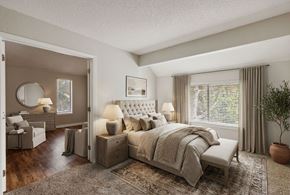 Kansas City apartment for rent - A bedroom with a large bed and a dressing table with a mirror.
